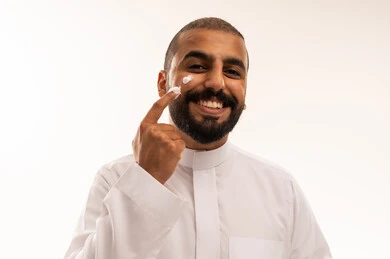 رجل سعودي بالثوب التقليدي يضع كريم البشرة