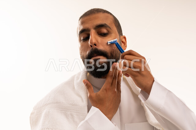 Saudi Man Shaving Beard with Razor in Traditional Thobe