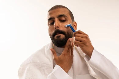 رجل سعودي يحلق لحيته بالثوب الأبيض التقليدي