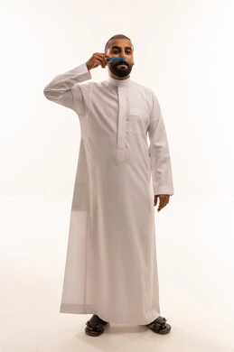 رجل سعودي بالثوب الأبيض يعتني بلحيته