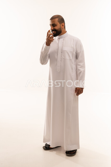 رجل سعودي بالثوب الأبيض يشم زجاجة عطر