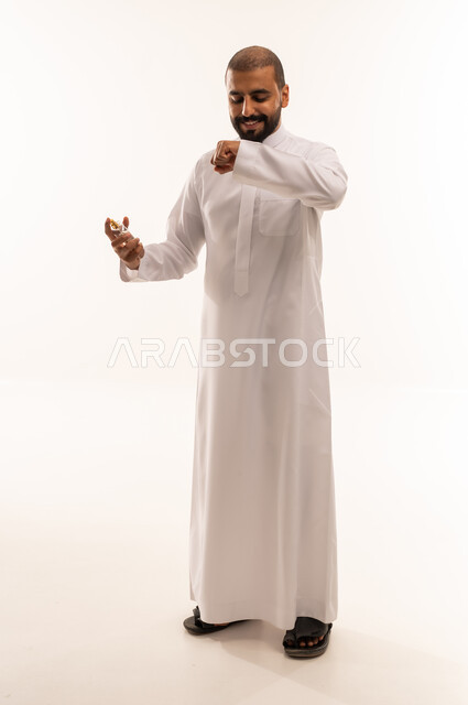 Saudi Man in White Thobe Smelling Perfume in Studio