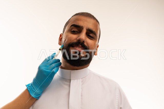 رجل سعودي يتلقى حقنة تجميلية للوجه في العيادة