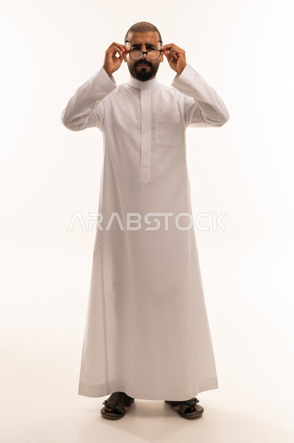 Saudi Man in Traditional White Thobe Adjusting Glasses