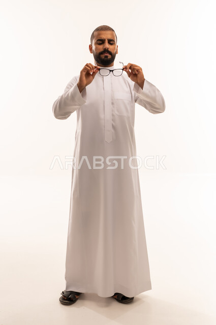 رجل سعودي بالثوب التقليدي يمسك نظارة طبية