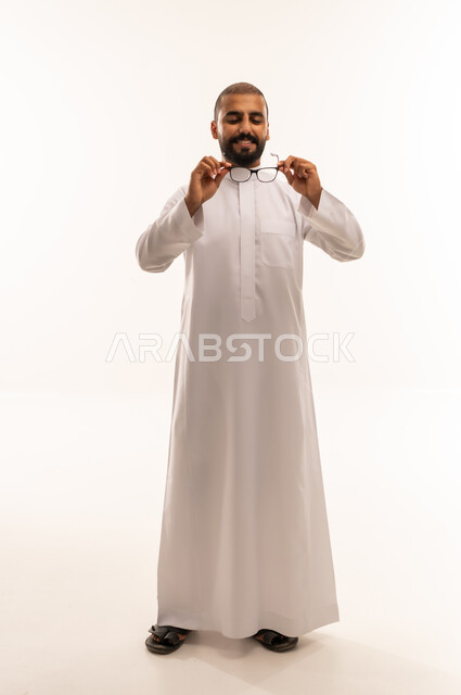 رجل عماني بالزي التقليدي يمسك نظارات طبية
