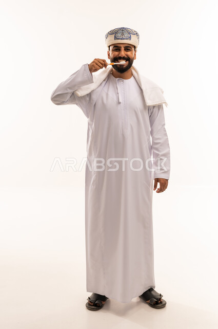 رجل عماني ينظف أسنانه بالدشداشة والكمة العمانية