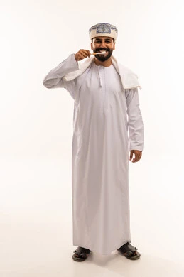رجل عماني ينظف أسنانه بالدشداشة والكمة العمانية