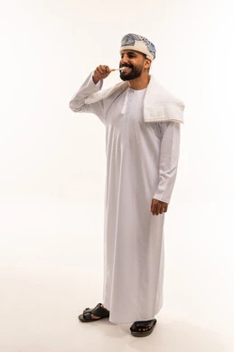 رجل عماني ينظف أسنانه بالفرشاة بالزي التقليدي