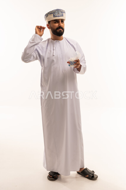 رجل عماني بالزي التقليدي يستخدم عود تنظيف الأذن