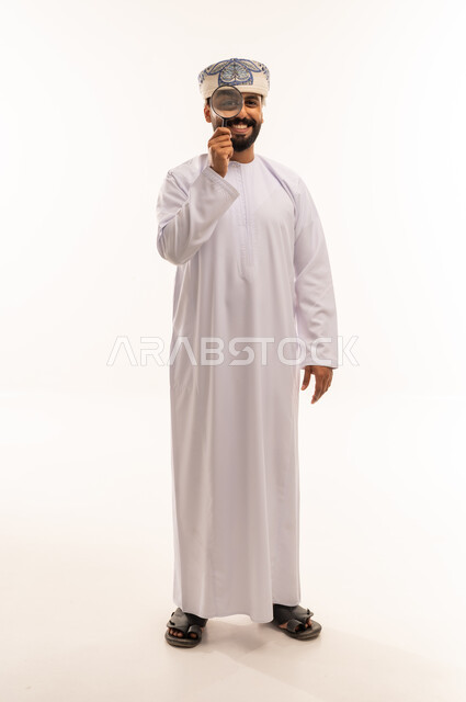 رجل عماني بالزي التقليدي يحمل عدسة مكبرة