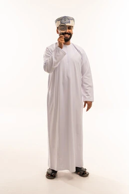 رجل عماني بالزي التقليدي يحمل عدسة مكبرة