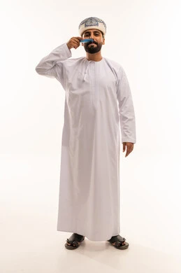 رجل عماني بالزي التقليدي يعتني بشنبه