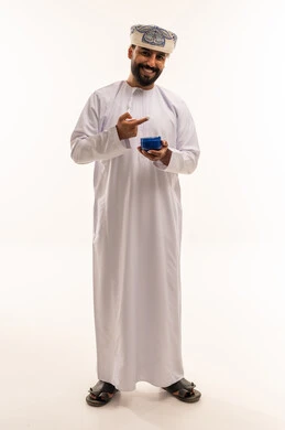 رجل عماني يحمل كريم للعناية بالبشرة خلفية بيضاء