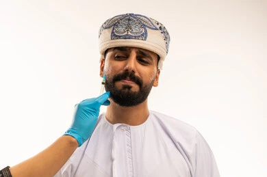 رجل عماني يتلقى حقنة تجميلية في عيادة طبية