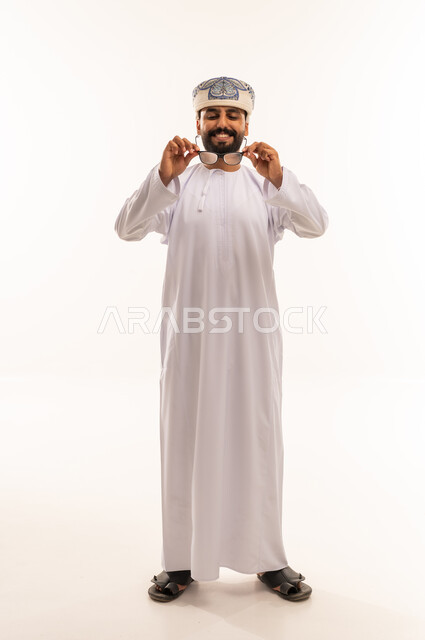 رجل عماني بالدشداشة التقليدية والكمة يمسك نظارة