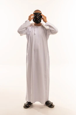 رجل عماني يرتدي قناع أسود بالدشداشة البيضاء