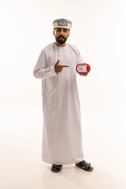 Omani Man Pointing at Red Alarm Clock on White Background