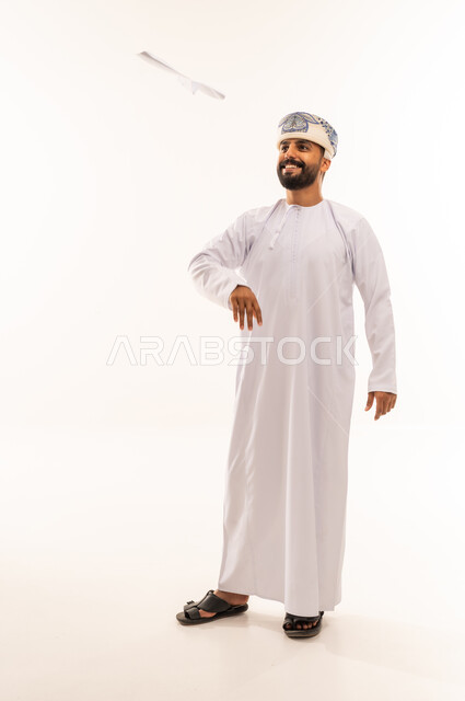 Omani Man in Traditional Dress Throwing Paper Airplane
