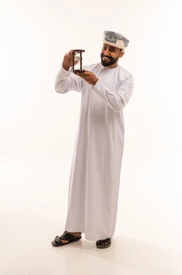 رجل عماني بالزي التقليدي يمسك ساعة رملية