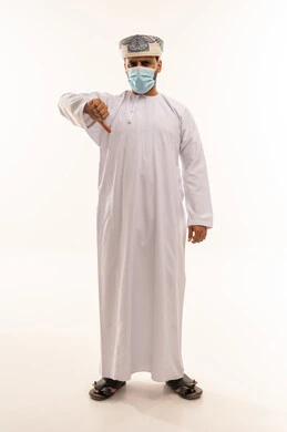 رجل عماني يرتدي كمامة ويشير بعلامة الرفض