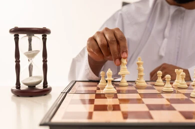 Omani Man Playing Chess Strategy with Hourglass