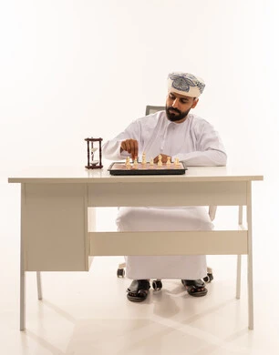 Omani Man Playing Chess with Strategy Hourglass