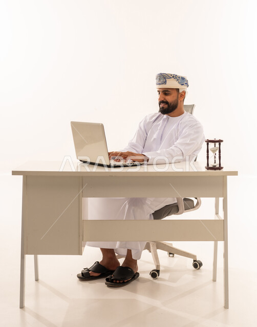 رجل عماني يستخدم الحاسوب المحمول في مكتب أبيض