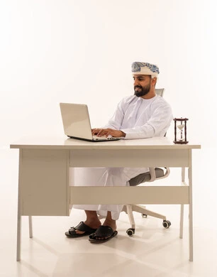 رجل عماني يستخدم الحاسوب المحمول في مكتب أبيض