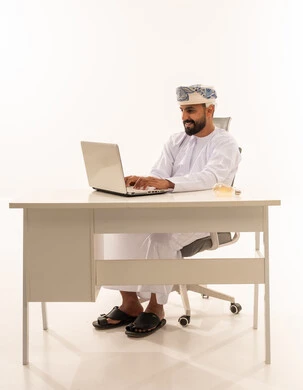 Omani Man Working on Laptop at White Office Desk