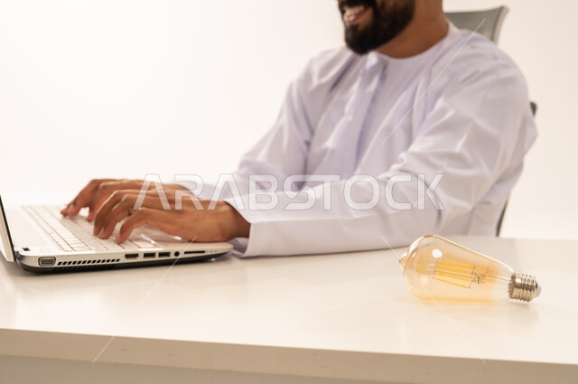 Omani Man Working on Laptop with Light Bulb