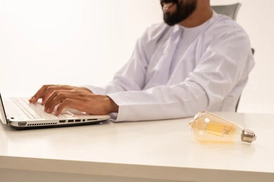 Omani Man Working on Laptop with Light Bulb