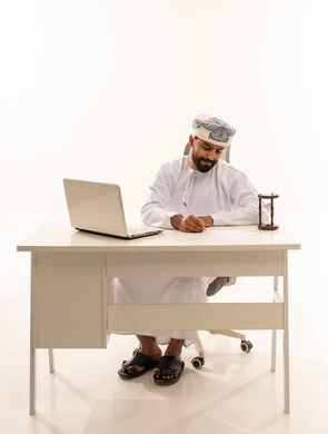 رجل عُماني بالزي التقليدي يكتب على مكتب عمل