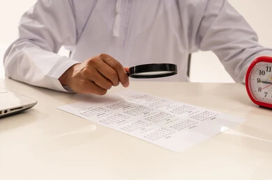 Omani Man Using Magnifying Glass to Check Calendar
