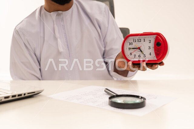 Omani Professional in Dishdasha Holding Red Alarm Clock