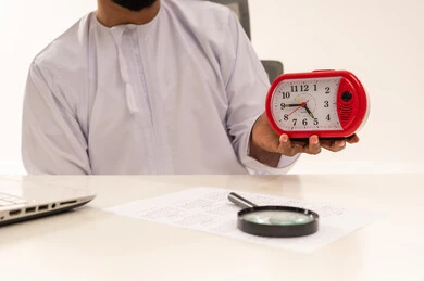Omani Professional in Dishdasha Holding Red Alarm Clock