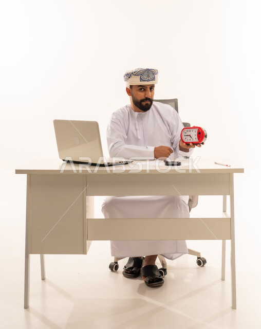 Omani Businessman Holding Alarm Clock at Office Desk