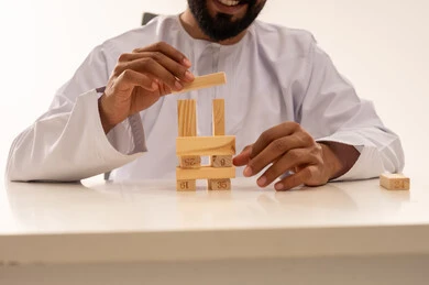 Omani Man Building Tower with Wooden Blocks Indoors