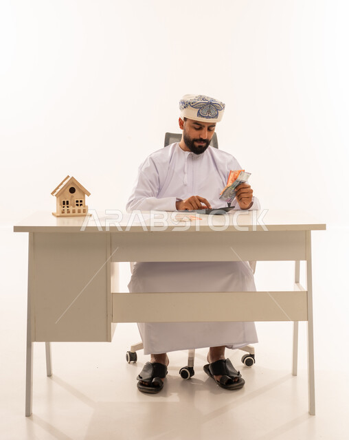 رجل عماني يحسب تكاليف شراء منزل بالمكتب