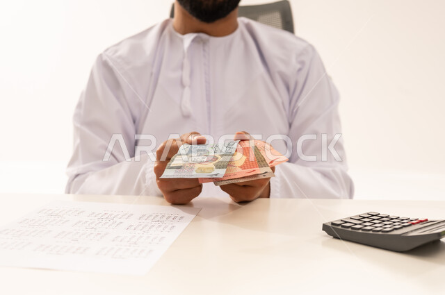 رجل عماني يعد الريال العماني في المكتب