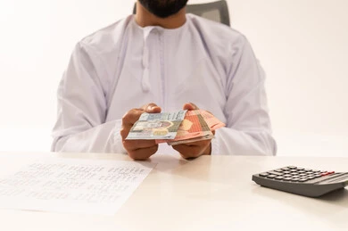رجل عماني يعد الريال العماني في المكتب