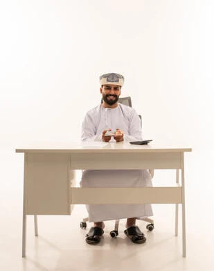 رجل عماني يمسك بالنقود على مكتب أبيض