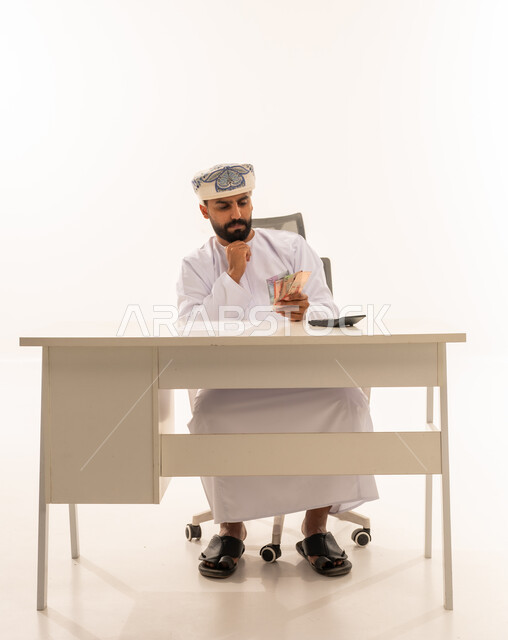 رجل عماني يحسب العملات الورقية على مكتب العمل
