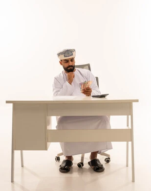 رجل عماني يحسب العملات الورقية على مكتب العمل