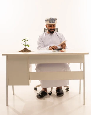 رجل عُماني يحسب الأرباح بالريال العُماني على مكتبه