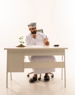 Omani Man at Desk with Money and Plant