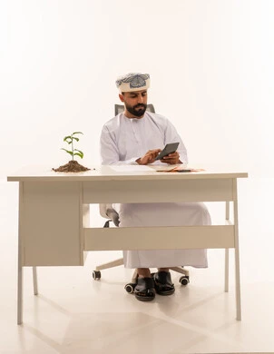 Omani Businessman Using Calculator at Office Desk