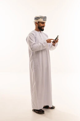 رجل عماني بالزي التقليدي يستخدم الهاتف المحمول