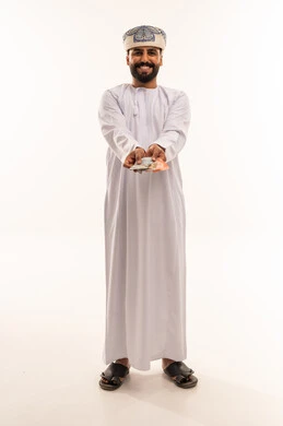 رجل عماني بالزي التقليدي يحمل عملات ورقية نقدية