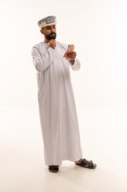 رجل عماني بالزي التقليدي يقوم بعد النقود الورقية